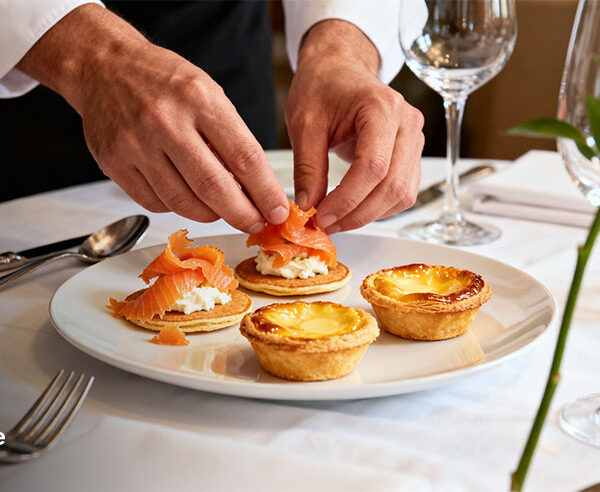 Chef plating French cuisine appetizers at a fine dining table