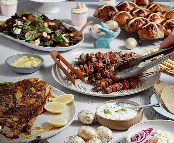 Easter lunch spread with grilled kebabs, roast fish, salad, hot cross buns, and flatbreads
