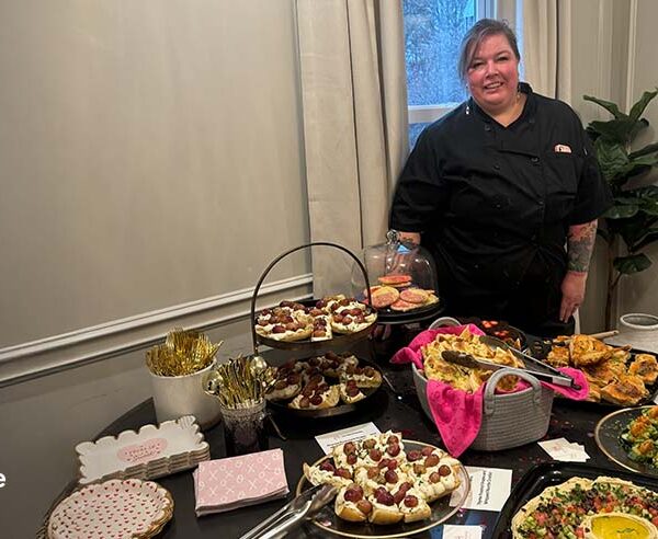 Chef Amanda Parks standing behind a spread of farm-to-table dishes at a private event in Columbus, Ohio
