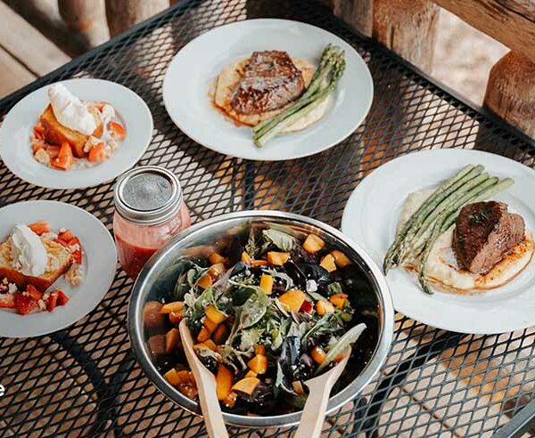 Personal chef service meal spread with steak, asparagus, salad, and strawberry dessert